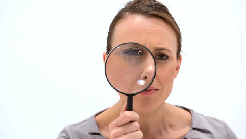 woman looking curiously with a magnifying glass