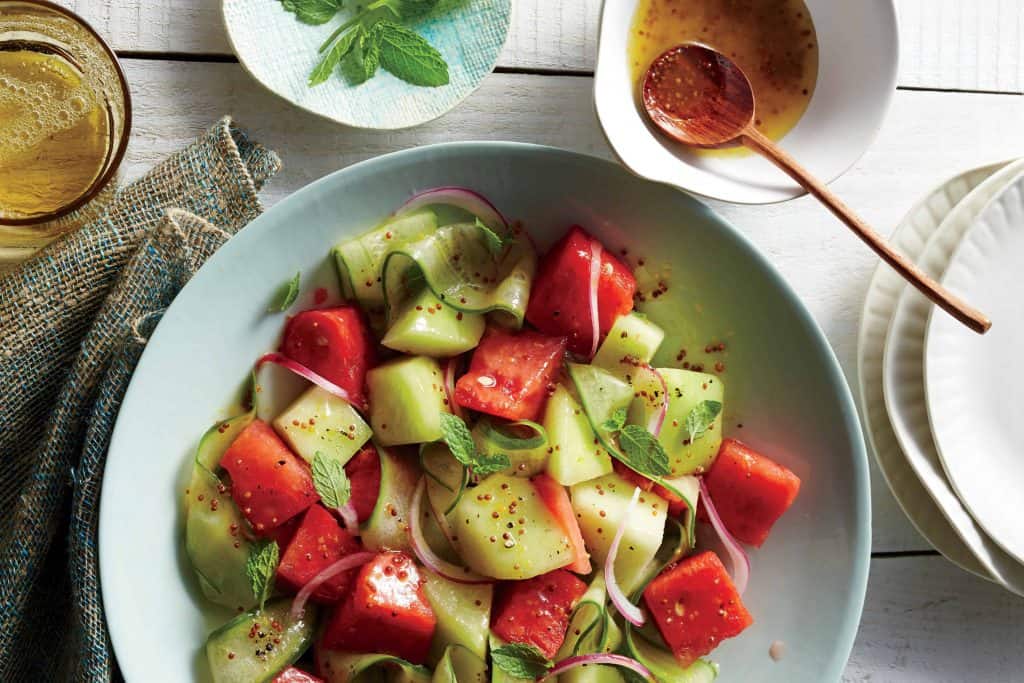 a salad bowl of watermelon, cucumber and honeydew with honey