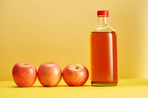 Apple-Cider-Vinegar-001 bottle of apple cider vinegar and fresh apple against yellow background