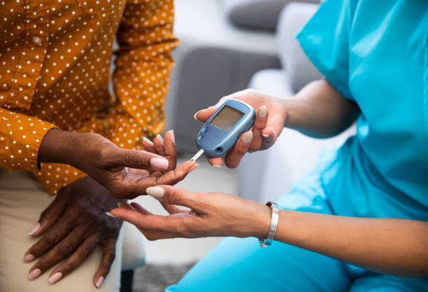 Young nurse doing a glucose blood test on her senior patient, during a home visit