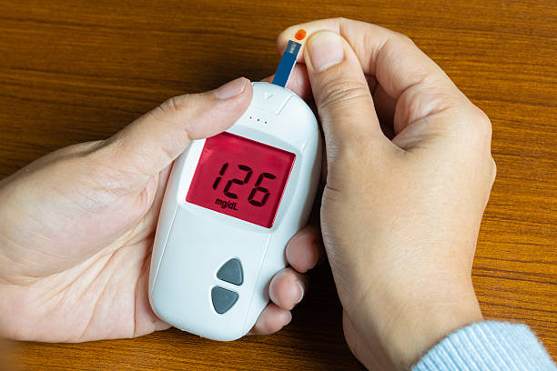 A woman draws blood on his finger and tests it for diabetes. Check high blood sugar levels with a digital blood sugar tester. Health care and medical concept