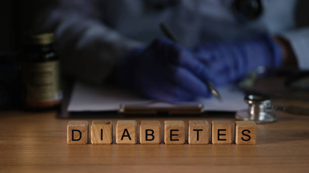 Diabetes-005-01-1 Doctor endocrinologist writing out prescription on background of wooden cubes with word diabetes closeup. Diagnosis and treatment of diabetes mellitus concept