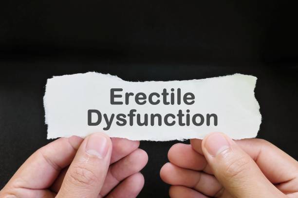 Erectile-Dysfunction-001-8-01 Erectile dysfunction diagnosis and anxiety concept. Male hand holding paper with written word text in black background.