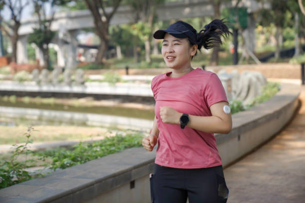 Day in the life of young woman with Continuous glucose monitor running in the park for her health.