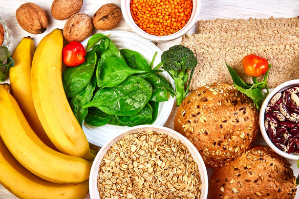 Set of high dietary fibre health food product concept with fruit, vegetables, whole wheat bread, legumes, cereals, nuts and seedson white wooden background . Top view, flat lay, copy space.