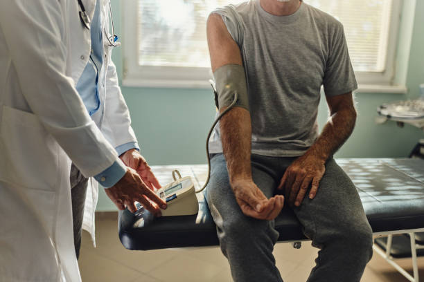 Unrecognizable male doctor measuring blood pressure of his patient in hospital.