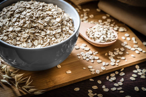 Oats-001 breakfast bowl full of oat flakes with a wooden spoon on wooden table