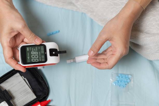 A woman's hand checking her blood sugar level with a glucometer by herself at her home.