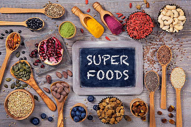 Superfoods in spoons and bowls on a wooden background