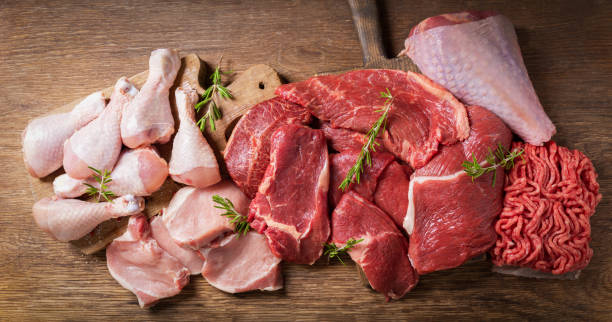various types of fresh meat: pork, beef, turkey and chicken on a wooden table, top view