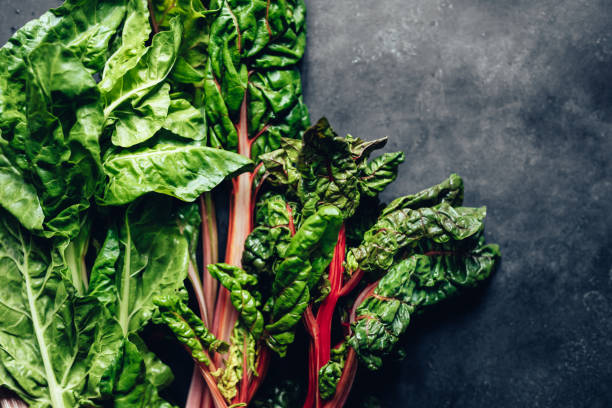 Close-up of spinach and chard leaves on black background. Green leafy vegetable on kitchen counter for preparing food.