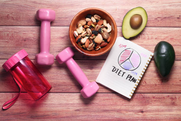 Diet plan with almond nut, dumbbells, avocado on table