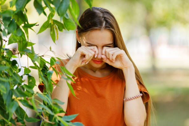 Beautiful Woman with Long Hair is Walking in Public Park and Rubbing her Eyes Due to the Problems with Allergy or Sight.