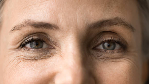 Close up view, upper face part of older pretty woman eyes, with signs of aging, advertises anti-wrinkles cream or cosmetology treatment to prevent fine lines under eyes. Wisdom, midlife, mature beauty