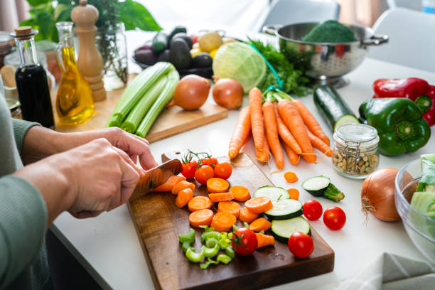Close up of woman's hands slicing fresh organic carrots on kitchen counter