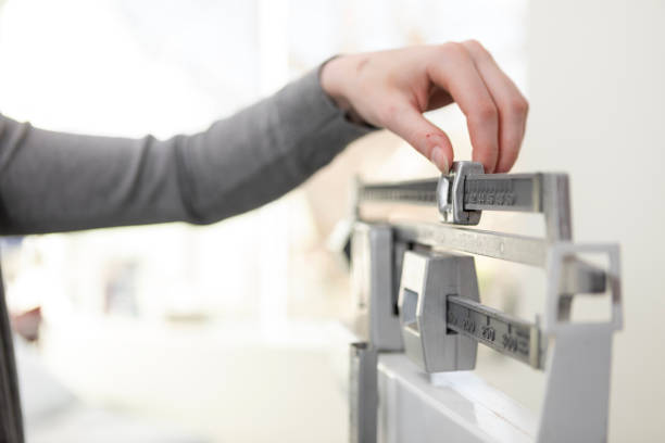 A close-up photo of an unrecognizable woman's hand as she adjusts the beam scale in the doctor's examination room.