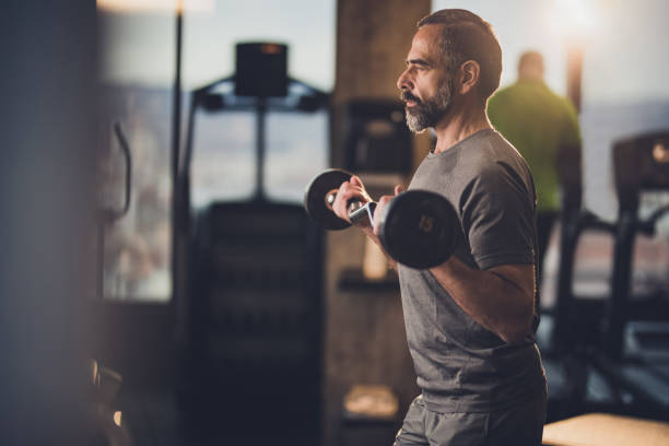 Determined mature man exercising with barbell in a health club.