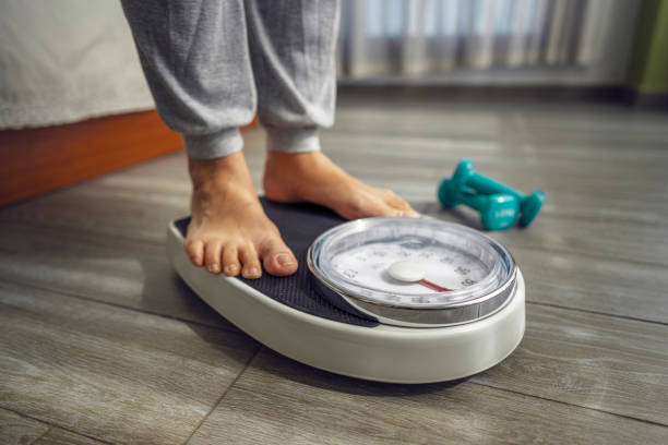 Close up of feet standing on weight scale.