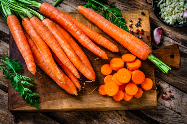 Overhead view of freshly sliced organic carrots on cutting board.
