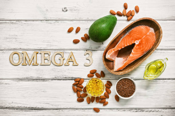 A set of foods high in omega-3 fatty acids on a white wooden background. Healthy eating concept. Salmon, avocado, flax seeds, fish oil capsules, oil, almonds. View from above