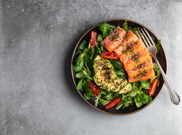 Salmon fish fillet with fresh salad, avocado top view.
